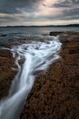 water flowing from the rocks out into the ocean along the coast