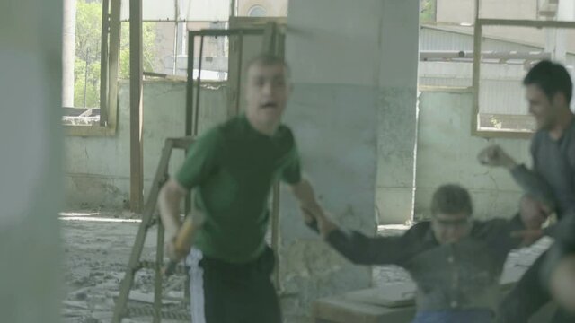 4k Group of men fighting in abandoned building . Friends helping each other during the fight . Drug deal between criminal gangs goes wrong & a fight breaks out .  Staged, scenic shot with artists