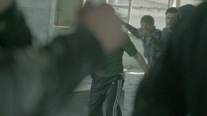 4k Group of men fighting in abandoned building . Friends helping each other during the fight . Drug deal between criminal gangs goes wrong & a fight breaks out .  Staged, scenic shot with artists