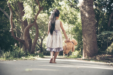 Sad girl hugging teddy bear sadness alone in green garden park. Lonely girl feeling sad unhappy...