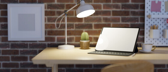 Industrial loft work space design, empty screen tablet under low light, red brick wall