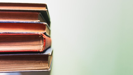 Old books over a pale green backdrop, and a clipboard. Copy space. 
