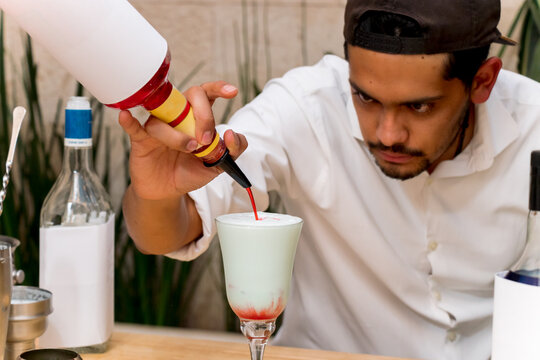 A Man Pouring Liquor In A Tall Glass Cup