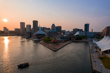 Fototapeta na wymiar Aerial View of Baltimore City Inner Harbor at Sunset with Boat Passing in the Water