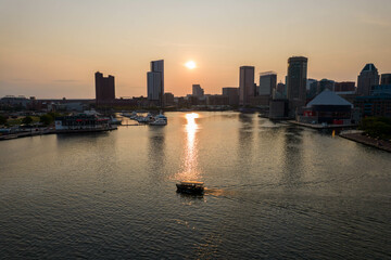 Fototapeta premium Aerial View of Baltimore City Inner Harbor at Sunset with Boat Passing in the Water