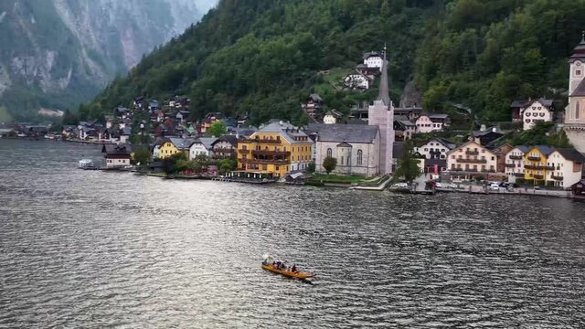 Aerial view of austrian mountain village Hallstatt and Hallstatter lake. Salzkammergut, Austria.  Traditional Flatboat or Rowing Boat on Lake Hallstatt, also called Fuhre with Tourists on a Cruise