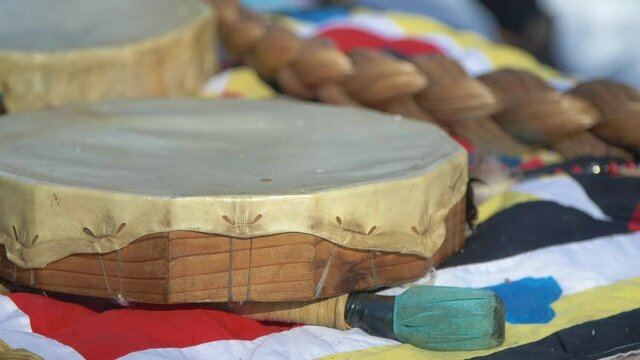 Close up on a native hand drum, drumstick and sweetgrass braid at a first nations ceremony, focused to burr shot.