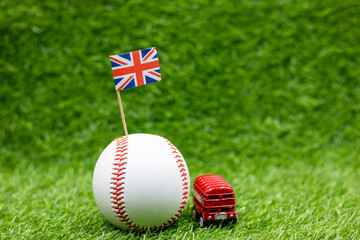 Baseball with Union Jack flag and double decker bus on green grass for London Concept