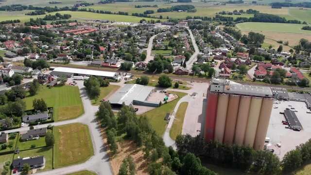 Aerial shot capturing the thriving agricultural industry in Brålanda with plenty of farmlands and a giant grains silos that belong to the major agribusiness Lantmännen Lantbruk in Sweden.