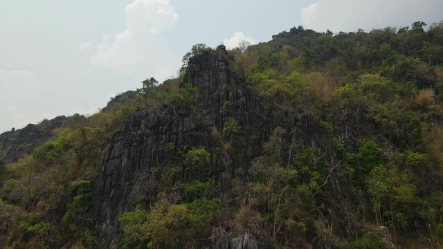 4K Aerial dolly in, spectacular view of limestone rock formation on the cliffside on rugged terrain in the mountains during a summer season in Thailand Southeast Asia.