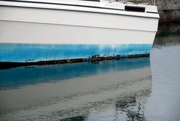 Fototapeta na wymiar Reflections of white and blue fishing boat docked at Westhaven Cove