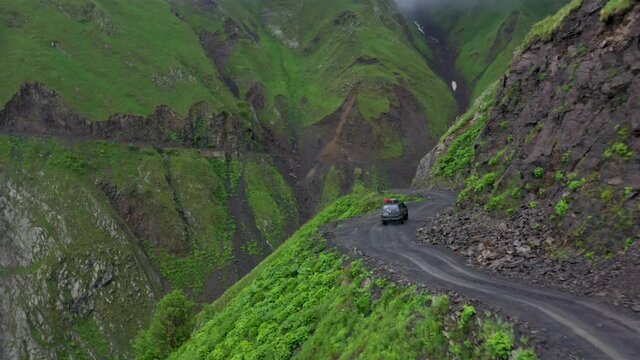 Dramatic drone shot of a vehicle driving on the Road to Tusheti, one of the worlds most dangerous roads