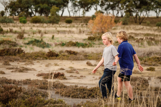 Brothers exploring desolate dry lake together. Family outing in the Australian bush.