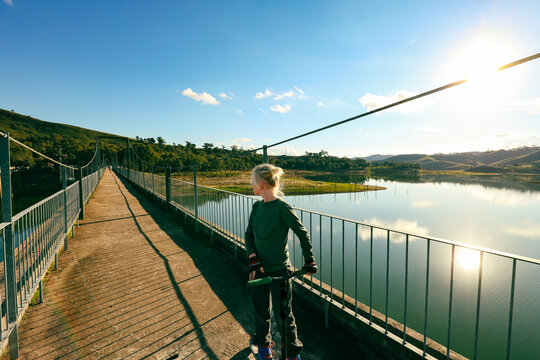 Boy riding scooter along the Mansfield-Tallarook Rail trail bridge over Lake Eildon at Bonnie Doon, Victoria Australia
