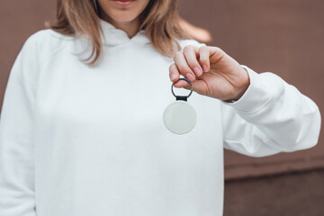 Keychain mockup in woman's hand. Blank round white sublimation keychain.
