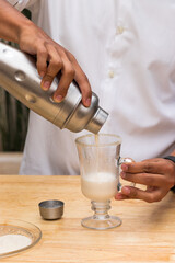 A man pouring milk into a glass cup