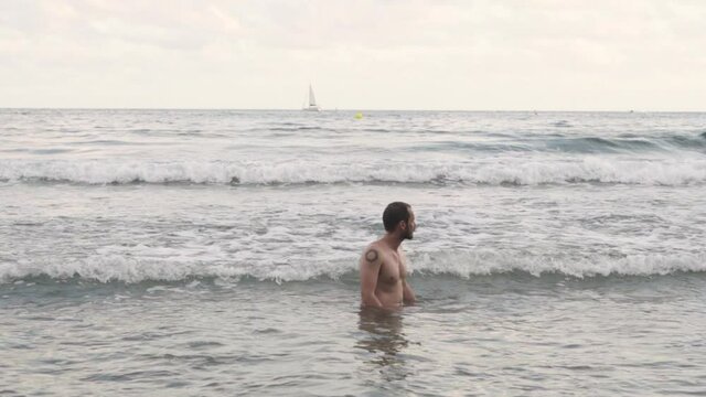 Handsome hispanic bathing off grid style at mediterranean sea Barcelona