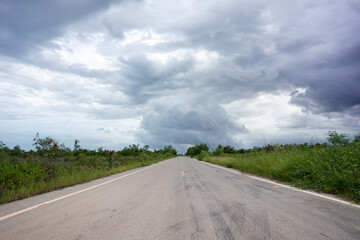 Driving on an empty road. Empty asphalt road through the green field and clouds on rainstorm in rainy season. Open road ahead, endless road for concept