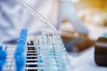 medical or scientific researcher researching and experimenting Multi-colored solution, vial and microscope In the laboratory or in the laboratory by wearing blue gloves and white clothing completely.