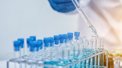 medical or scientific researcher researching and experimenting Multi-colored solution, vial and microscope In the laboratory or in the laboratory by wearing blue gloves and white clothing completely.