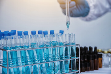 medical or scientific researcher researching and experimenting Multi-colored solution, vial and microscope In the laboratory or in the laboratory by wearing blue gloves and white clothing completely.