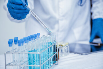 medical or scientific researcher researching and experimenting Multi-colored solution, vial and microscope In the laboratory or in the laboratory by wearing blue gloves and white clothing completely.