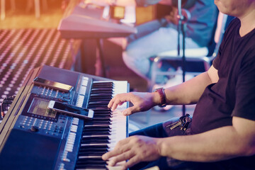 Musician play electronic keyboard synthesizers by using smartphone as guidelines for playing on the concert stage. Selective focus on smartphone.