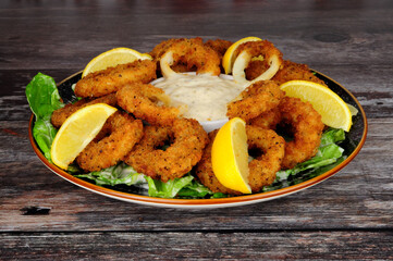 Breadcrumb covered salt and pepper calamari squid rings with tartar dipping sauce and fresh lemons