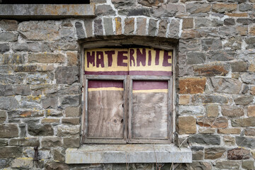 Focus on window with painted woodwork and the word "maternité", French for maternity.