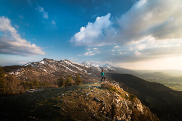 Woman alone standing at the edge of cliff in vercors mountain range at sunset