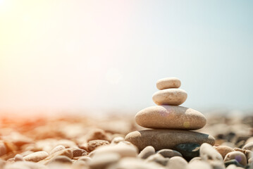 Fototapeta na wymiar Zen stones are background. A pyramid of pebble stones against the background of the sky, sea and beach. Meditation, yoga, calming the mind and relaxation concept.