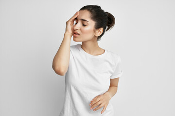 brunette in a white t-shirt holding her head discontent depression pain