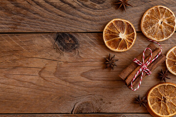 Cinnamon sticks, slices of dried orange, star anise on wooden background with copy space. Top view....