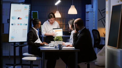 Diverse multi-ethnic businesspeople analyzing management graphs using tablet for company...