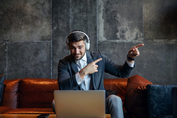 Businessman having a video call with business partners. He pointing to the right and having...