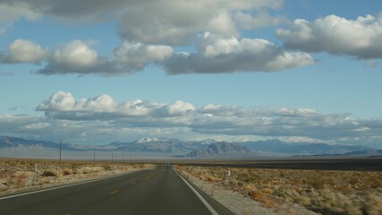 Road trip, driving auto from Death Valley to Las Vegas, Nevada USA. Hitchhiking traveling in America. Highway journey, dramatic atmosphere, clouds, mountain and Mojave desert wilderness. View from car