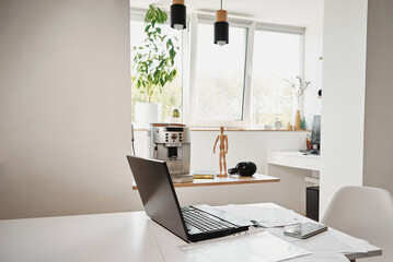 Open laptop on the kitchen table in home interior. Home office, remote work. Freelancer workplace