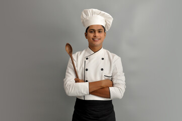 Happy male chef dressed in uniform holding wooden spoon