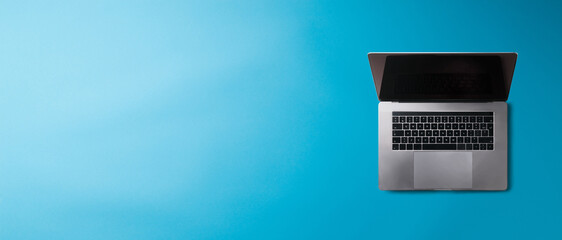 Flat lay top view office desk working space with laptop on blue background. Copy space.