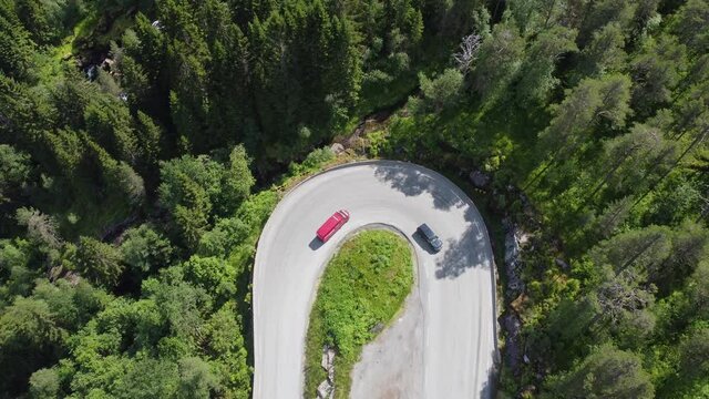 Winding roads at E39 F&oslash;rde Norway - Ascending top-down aerial of 180 degree curve with traffic climbing up mountain inside evergreen forest