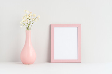 Blank pink portrait frame mock up and a pink vase with gypsophila flowers