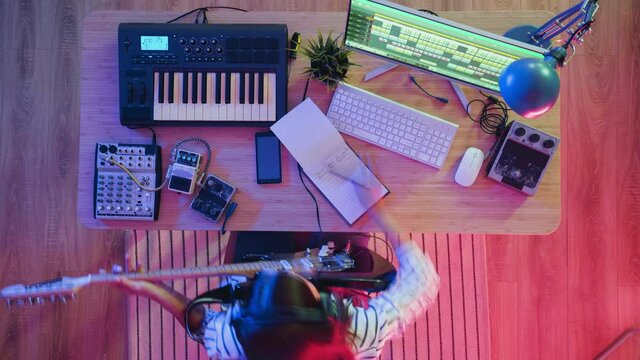 Top view time lapse of young woman playing electric guitar creating music indoors at table at home. Youth culture and musical instruments concept.