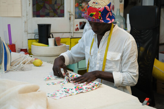 An african tailor cutting fabric in his sewing shop.