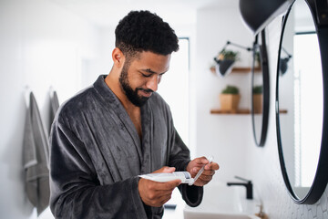 Young man brushing teeth indoors at home, morning or evening routine concept.