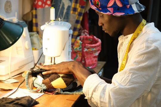 African tailor sewing a hat with sewing machine at sewing workshop.