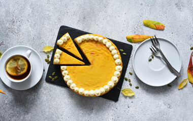 Delicate cheesecake with pumpkin on a wooden board on a concrete background.