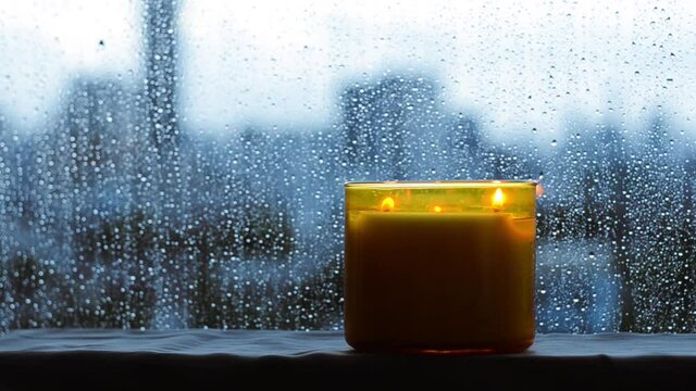 Burning aroma candle puts near by window that have rain drop in monsoon season. Zen and relax concept.