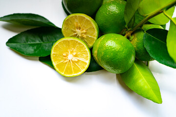 Limes,Half of lime citrus fruit, which is typically round, green in color with leafs  on isolated white background.Lime juice is used to make limeade and as an ingredient in many cocktail.