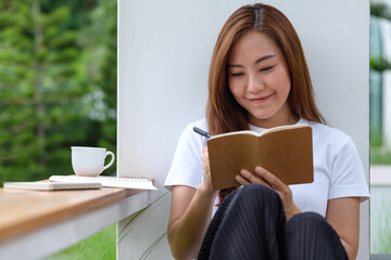 A beautiful young asian woman writing on notebook in the outdoors