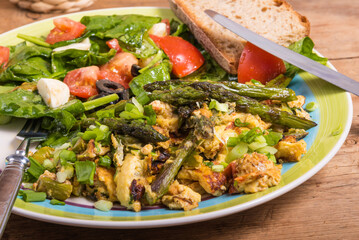Scrambled eggs with asparagus and vegetable salad on a plate close-up - quick breakfast